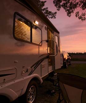 Luxury travel trailer parks on grass as sun sets
