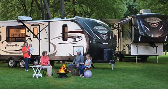 Family sits outside in front of two RVs and learns about travel trailers